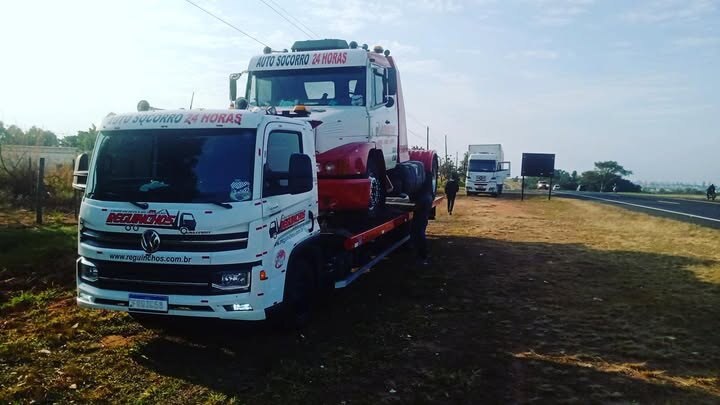 Guincho pesado transportando caminhão vermelho em área aberta